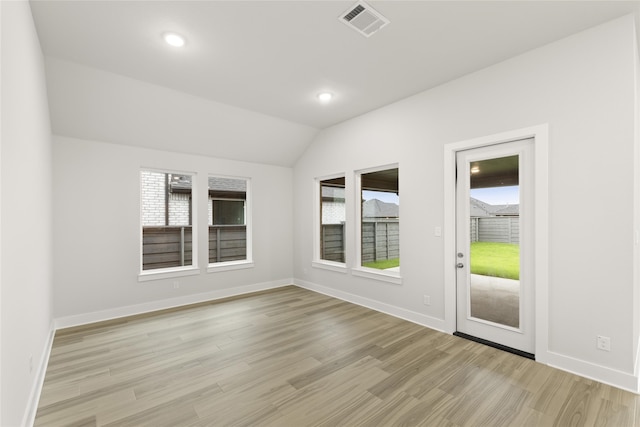 spare room with light hardwood / wood-style floors and vaulted ceiling