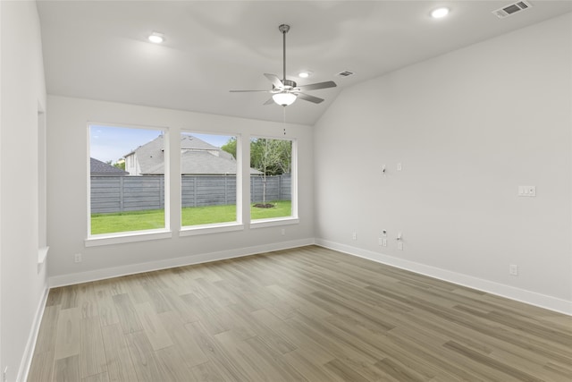 empty room featuring light hardwood / wood-style floors, vaulted ceiling, and a wealth of natural light