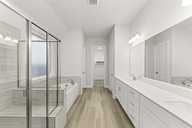 bathroom featuring independent shower and bath, hardwood / wood-style floors, and dual bowl vanity