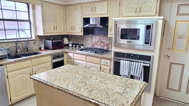 kitchen featuring light stone countertops, appliances with stainless steel finishes, tasteful backsplash, wall chimney exhaust hood, and sink