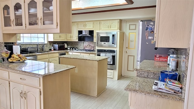 kitchen featuring a center island, ornamental molding, backsplash, wall chimney range hood, and stainless steel appliances