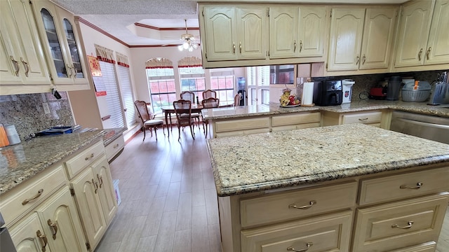 kitchen featuring ceiling fan, light hardwood / wood-style floors, tasteful backsplash, crown molding, and kitchen peninsula