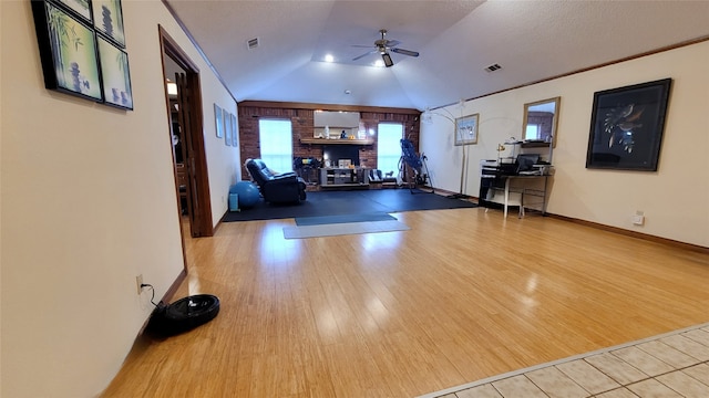 unfurnished living room with ceiling fan, light hardwood / wood-style flooring, vaulted ceiling, and brick wall