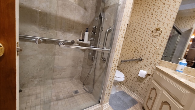 bathroom featuring a shower with door, vanity with extensive cabinet space, and toilet