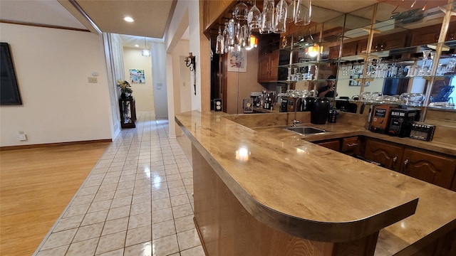 bar featuring dark brown cabinetry and light wood-type flooring