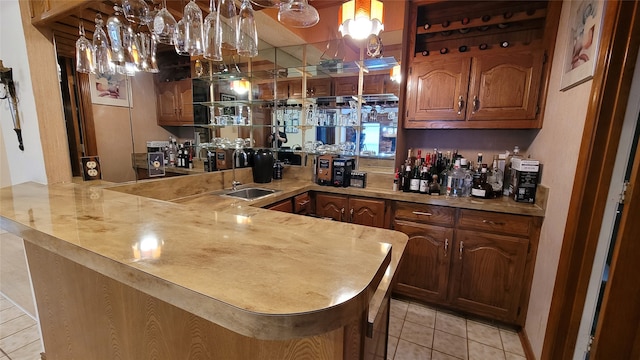 kitchen featuring sink, kitchen peninsula, light tile floors, and pendant lighting