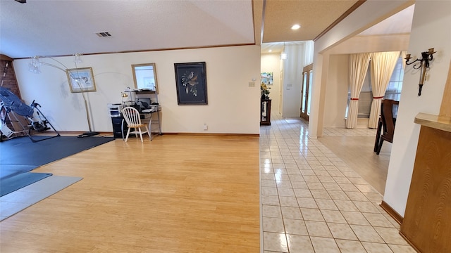 workout area with ornamental molding, light tile flooring, and a textured ceiling