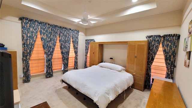 carpeted bedroom featuring ceiling fan and a tray ceiling