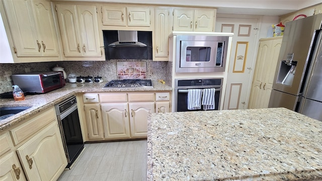 kitchen featuring wall chimney exhaust hood, tasteful backsplash, appliances with stainless steel finishes, and light stone counters