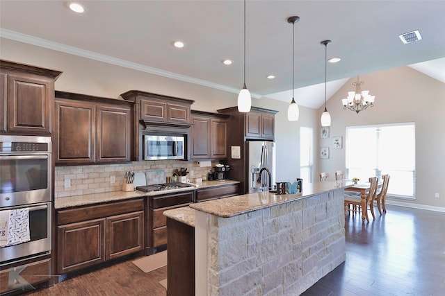 kitchen featuring pendant lighting, dark wood-type flooring, stainless steel appliances, tasteful backsplash, and lofted ceiling