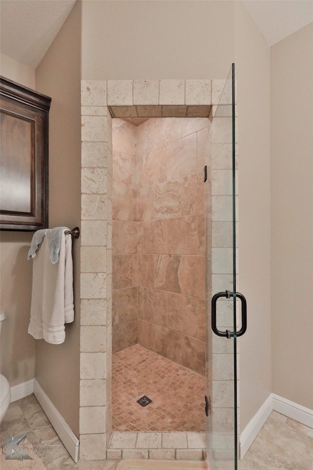 bathroom featuring a shower with shower door, toilet, and tile floors