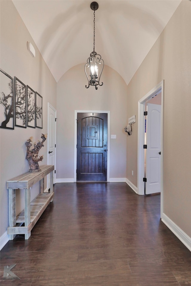 entryway featuring dark wood-type flooring, a notable chandelier, and lofted ceiling