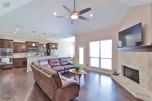 living room with dark hardwood / wood-style floors, ceiling fan, vaulted ceiling, and a stone fireplace