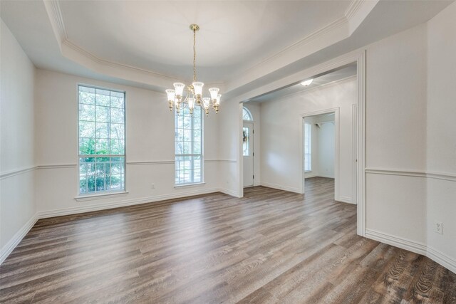 empty room with wood-type flooring, a raised ceiling, and crown molding