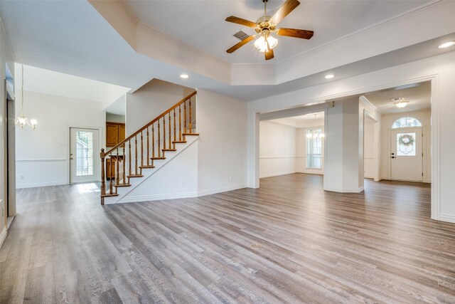 unfurnished living room with light wood-type flooring, a tray ceiling, ceiling fan, and crown molding