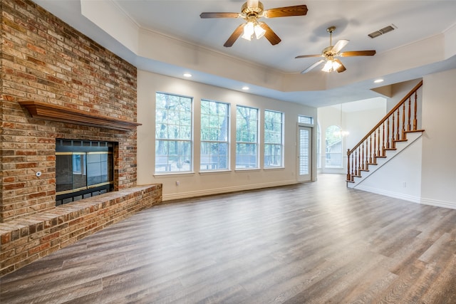 unfurnished living room with hardwood / wood-style floors, a fireplace, ceiling fan with notable chandelier, and ornamental molding