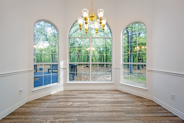 unfurnished dining area featuring wood-type flooring and a chandelier