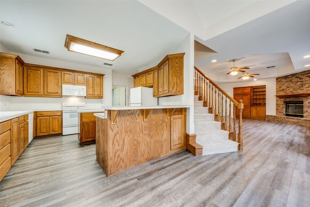 kitchen featuring a kitchen breakfast bar, white appliances, ceiling fan, and light hardwood / wood-style floors