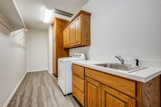 clothes washing area with cabinets, light hardwood / wood-style floors, sink, and washer / clothes dryer