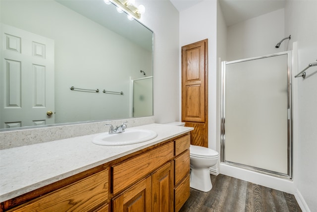 bathroom with toilet, vanity, wood-type flooring, and a shower with door