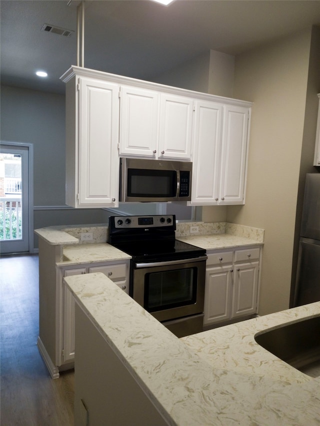 kitchen featuring appliances with stainless steel finishes, wood-type flooring, and white cabinetry