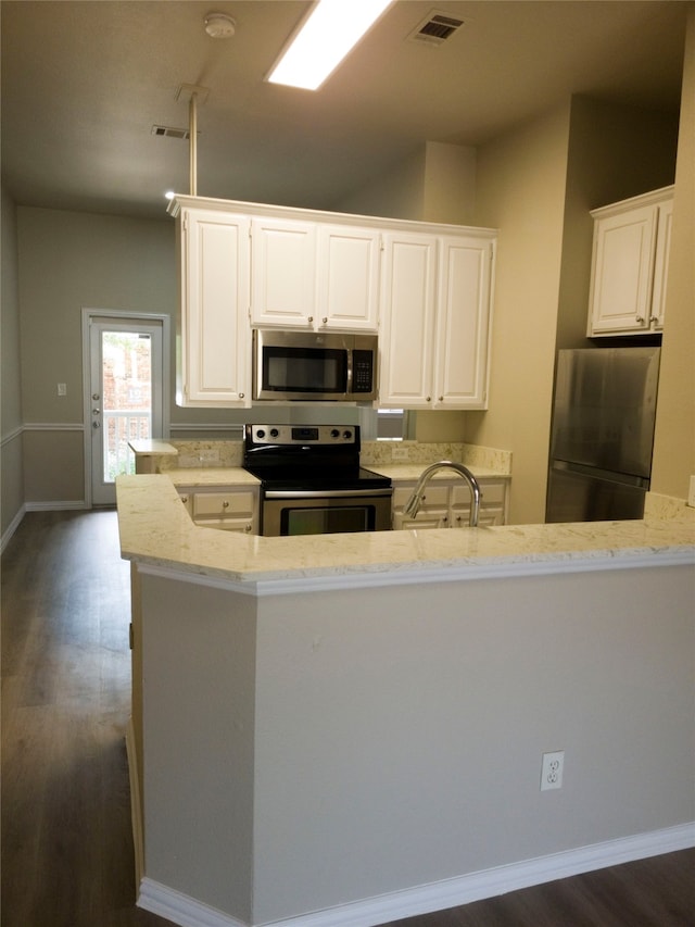 kitchen with light stone countertops, appliances with stainless steel finishes, dark wood-type flooring, white cabinetry, and sink