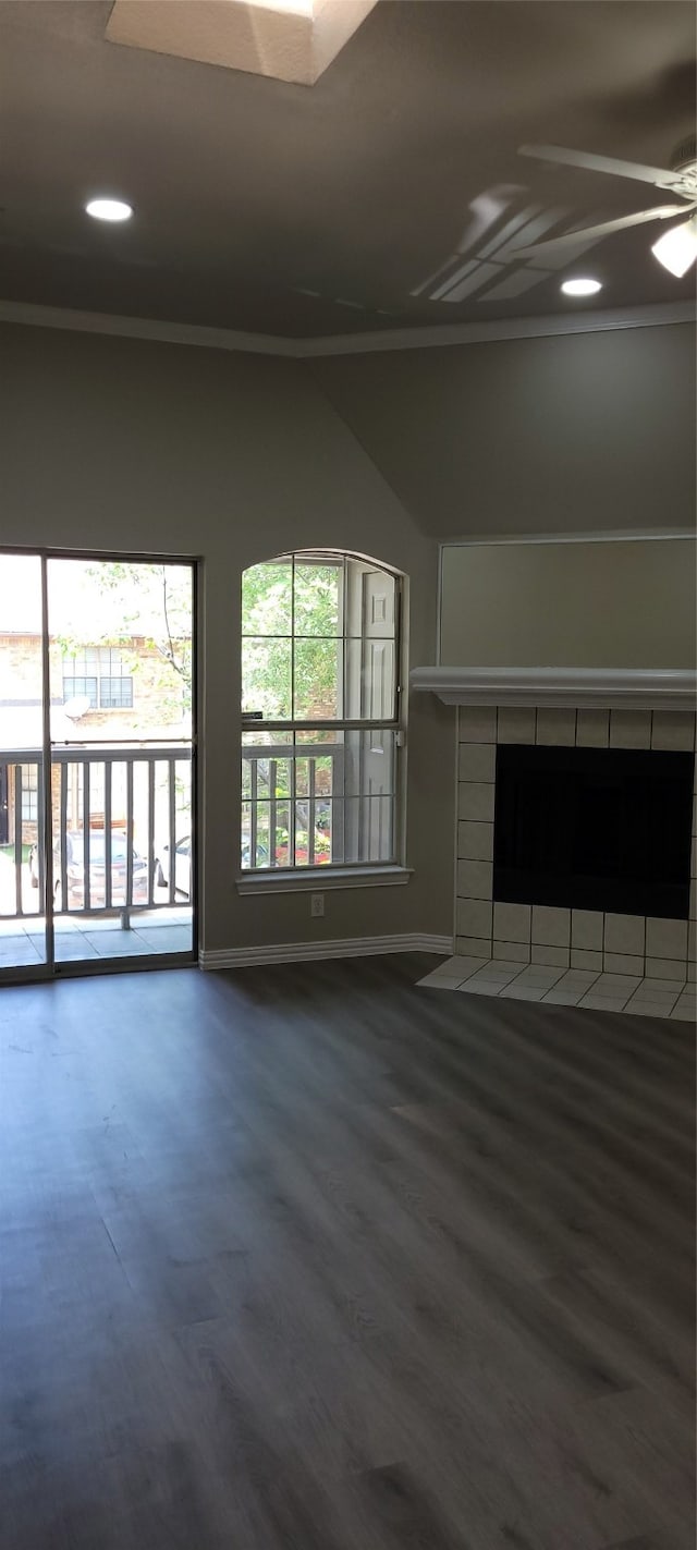 unfurnished living room featuring dark hardwood / wood-style flooring, ceiling fan, and a tile fireplace