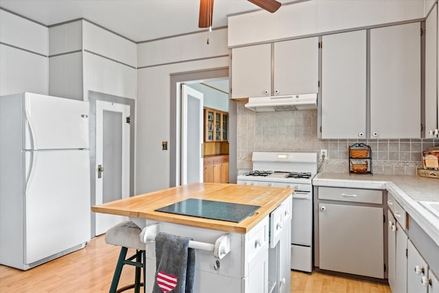 kitchen with white appliances, backsplash, light hardwood / wood-style floors, tile countertops, and ceiling fan