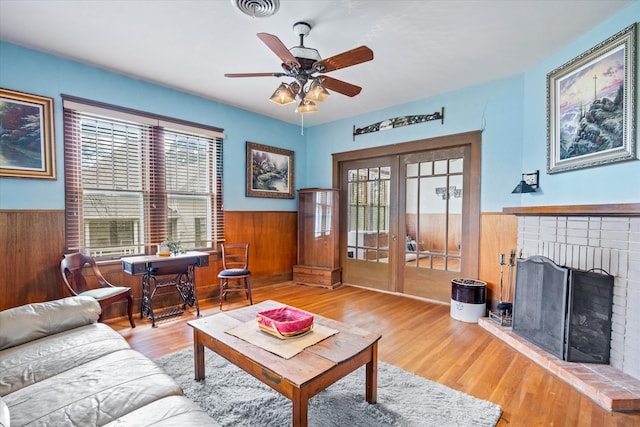 living room featuring a fireplace, french doors, ceiling fan, and light wood-type flooring