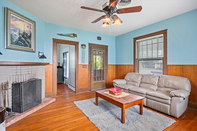 living room with a fireplace, hardwood / wood-style floors, ceiling fan, and a baseboard radiator