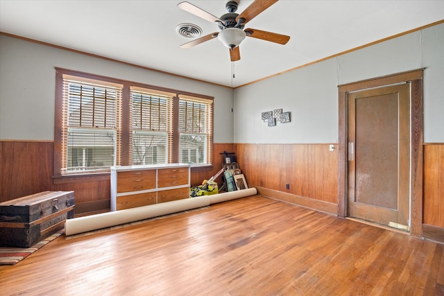 unfurnished room with wood-type flooring, wood walls, ceiling fan, and crown molding