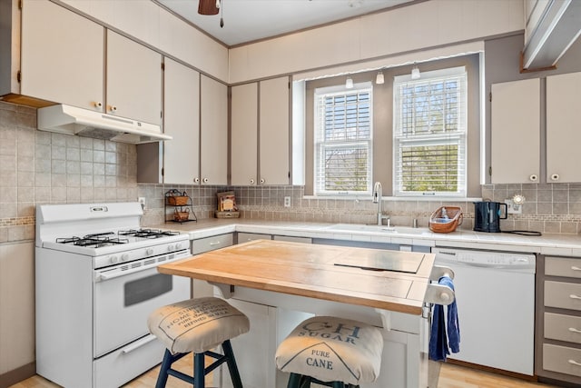 kitchen with ceiling fan, sink, white appliances, tasteful backsplash, and light wood-type flooring