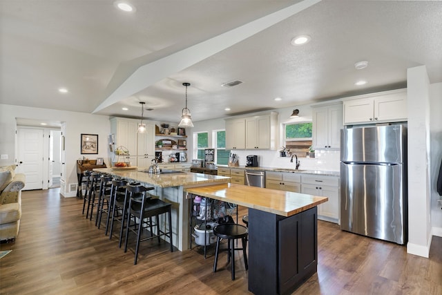 kitchen with dark hardwood / wood-style floors, hanging light fixtures, a center island, white cabinets, and appliances with stainless steel finishes