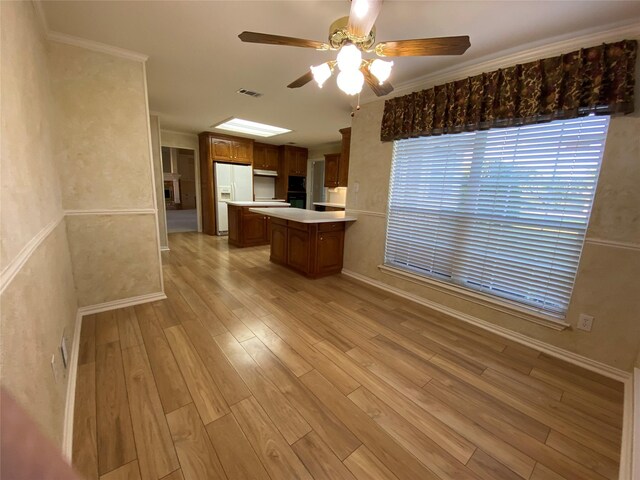 kitchen with light wood-type flooring, white refrigerator with ice dispenser, ceiling fan, and kitchen peninsula