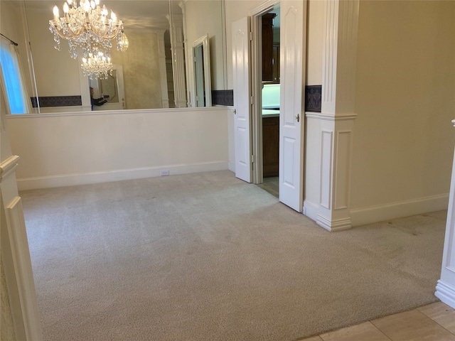 carpeted spare room featuring an inviting chandelier