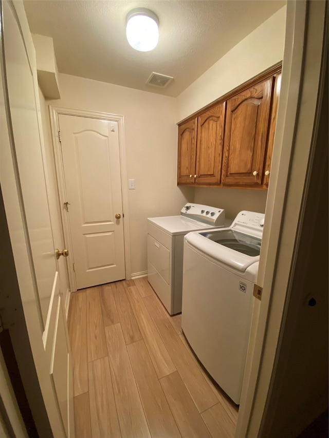 laundry area with cabinets, washing machine and dryer, and light wood-type flooring