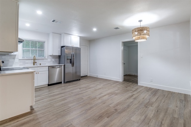 kitchen featuring white cabinets, light hardwood / wood-style floors, appliances with stainless steel finishes, and backsplash