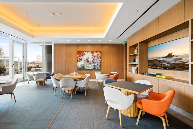 interior space featuring wooden walls, a tray ceiling, and dark colored carpet