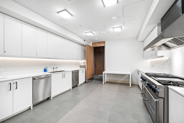 kitchen with white cabinets, stainless steel appliances, wall chimney range hood, and light tile floors