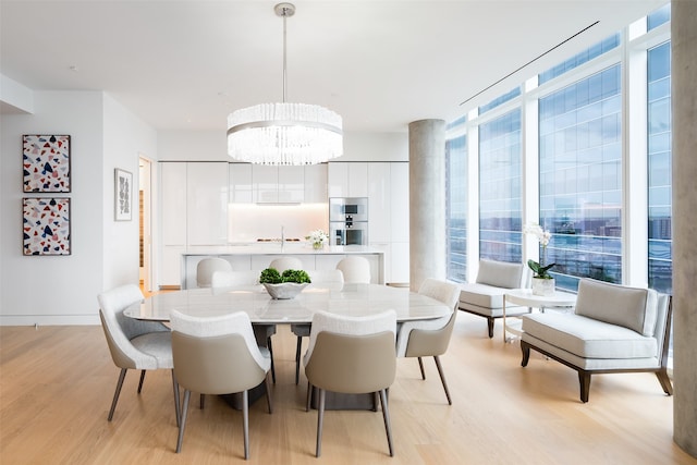 dining space featuring floor to ceiling windows, sink, light wood-type flooring, and an inviting chandelier