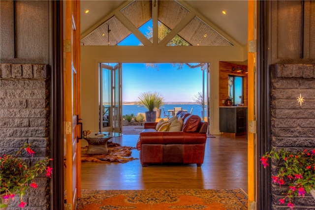 living room with a water view, high vaulted ceiling, and hardwood / wood-style flooring