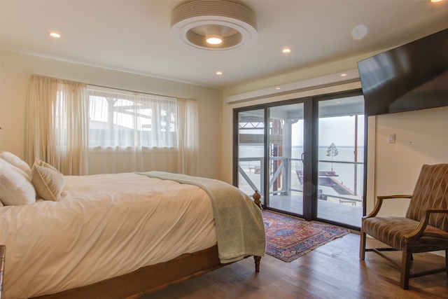 bedroom featuring hardwood / wood-style floors, a water view, and access to exterior