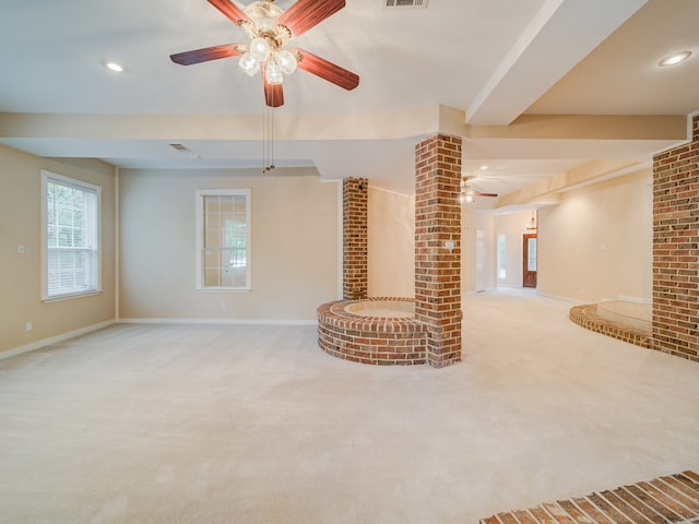 unfurnished living room featuring ceiling fan, carpet floors, and brick wall