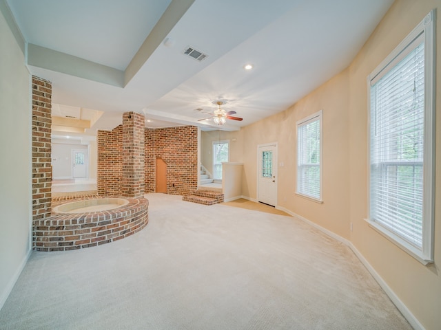 unfurnished living room with carpet flooring, brick wall, and ceiling fan