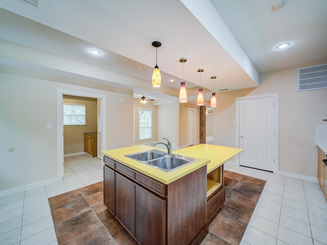 kitchen with light tile flooring, hanging light fixtures, a center island with sink, ceiling fan, and sink