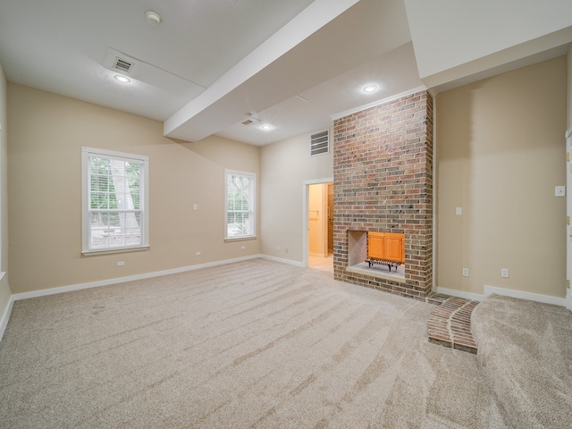 unfurnished living room featuring brick wall, carpet floors, and a fireplace