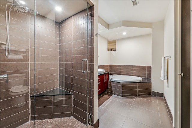 bathroom featuring tile flooring, independent shower and bath, and vanity