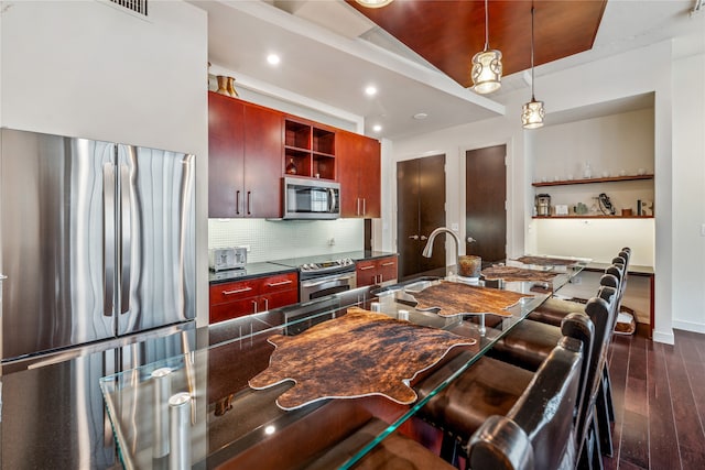 kitchen with decorative light fixtures, dark hardwood / wood-style floors, backsplash, stainless steel appliances, and sink