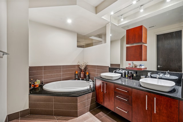 bathroom with tile flooring, vanity with extensive cabinet space, double sink, and tiled bath