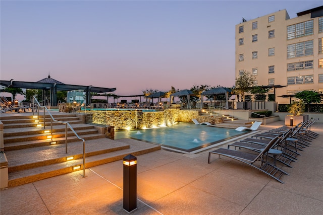 pool at dusk with a patio area